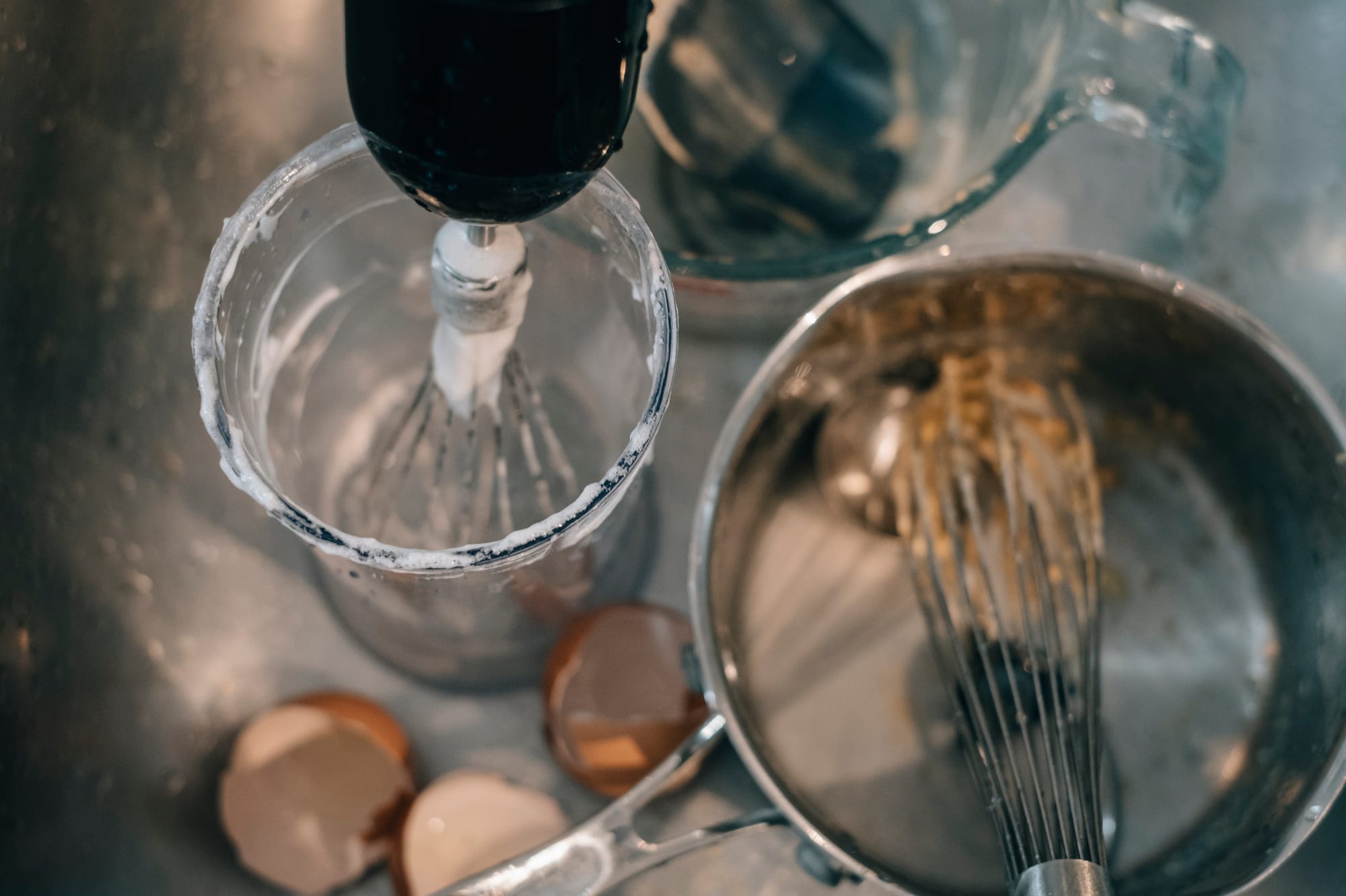 egg shells, whisks, pans and bowls in a sink, waiting to be washed after being used to mix up a cake