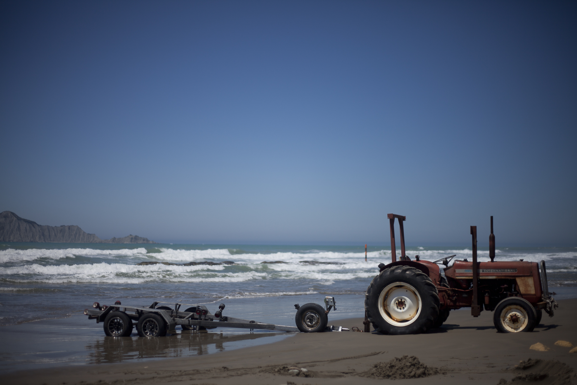 A tractor and trailer parked on Waimarama Beach, New Zealand - photo, copyright, leonie wise