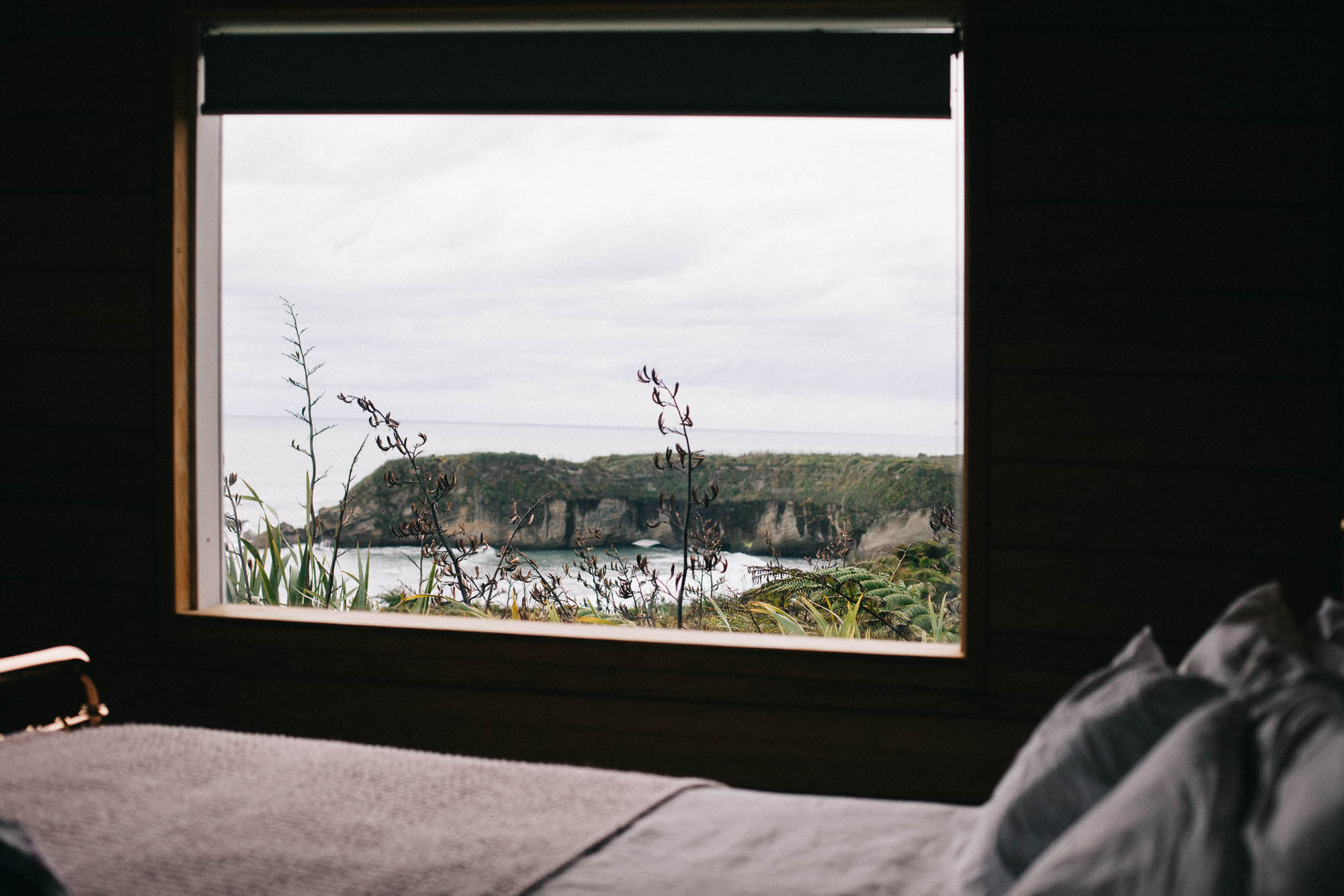 Bed and window with a view down to the bay below at Woodpecker Hut (c) Leonie Wise