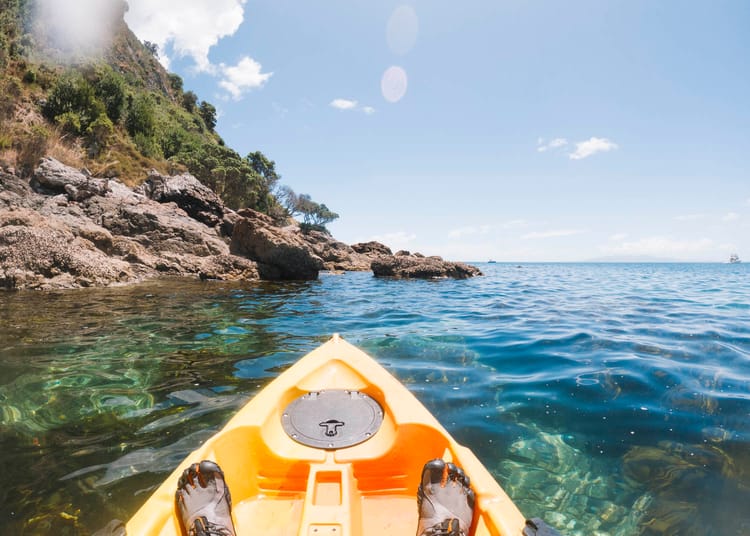 Feet in a kayak looking towards a headland. Photo © Leonie Wise