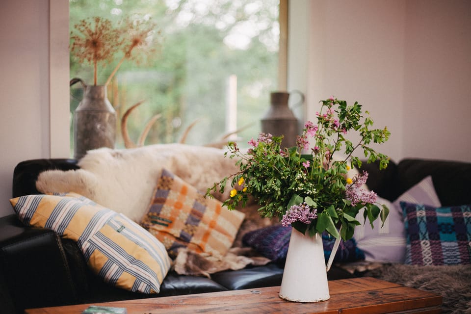 Wildflowers in enamel jug with sofa in background. By Leonie Wise