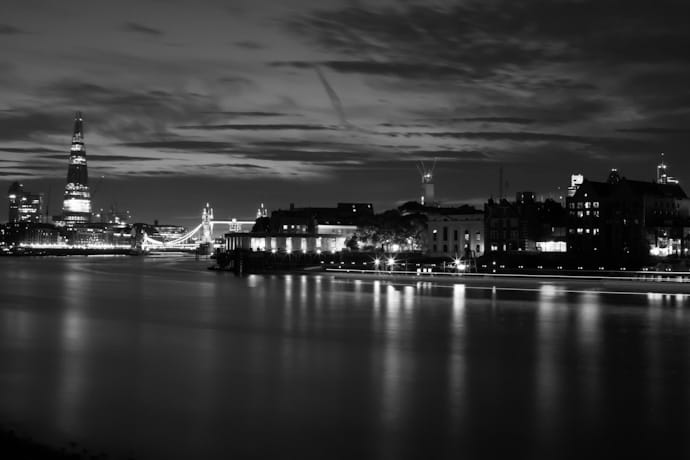 a monochrome image of the thames river - looking towards tower bridge and the shard