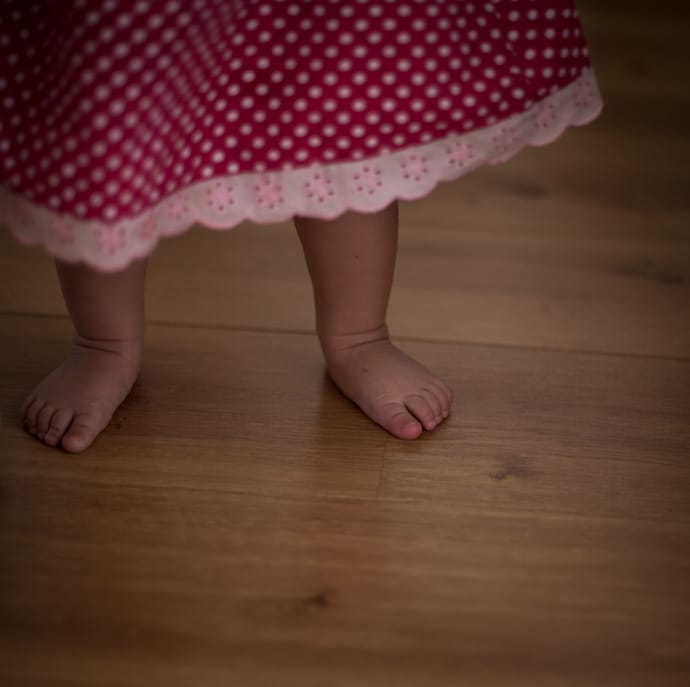 baby feet and a pink polka-dot dress with white trimmed hem