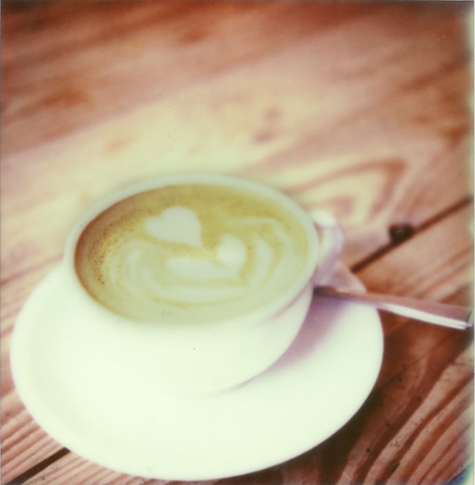 polaroid image of a flat white coffee sitting on a wooden table. copyright leonie wise
