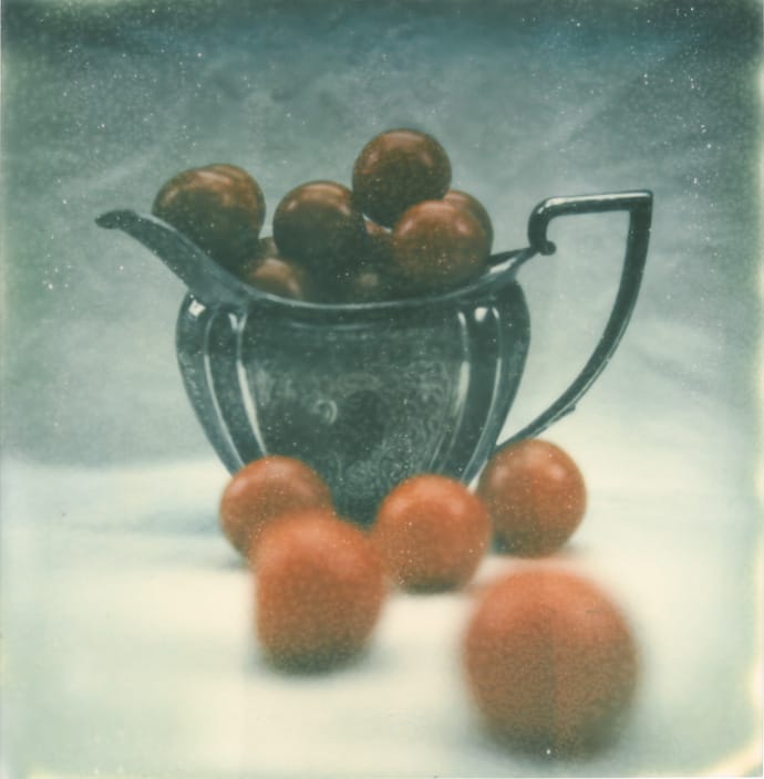 polaroid photograph of small tomatoes in a silver jug. copyright leonie wise