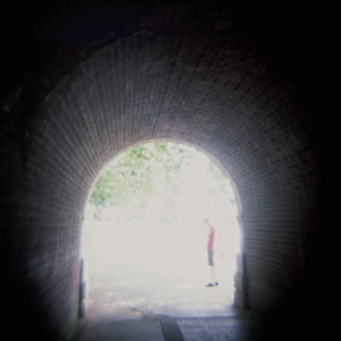 holga photograph of a tunnel with a person standing at the end of it in the light. copyright leonie wise